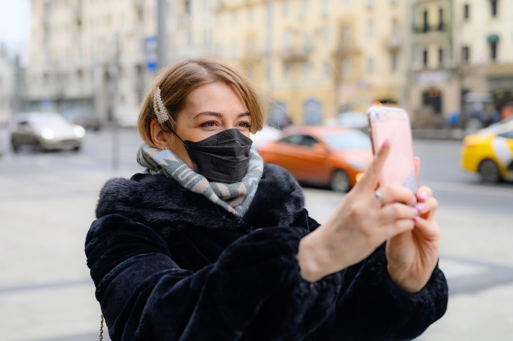 a woman in a black medical mask takes a selfie photo on a city outdoor winter woman selfie mask t Gxppe
