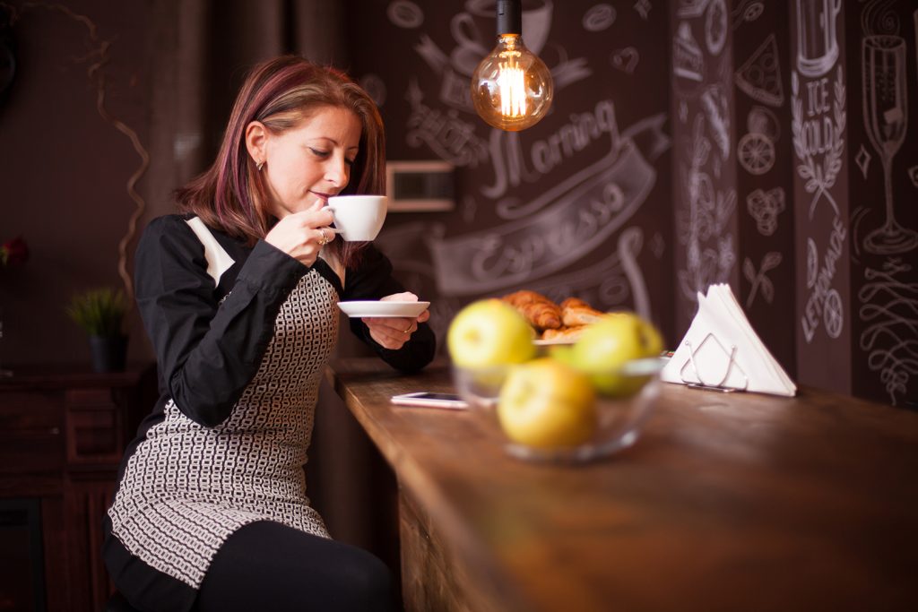 adult woman enjoys her cup of coffe at bar counter EYLZM